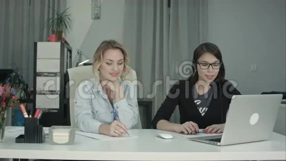 高级女经理在工作时看耳机里的实习生并做笔记视频的预览图
