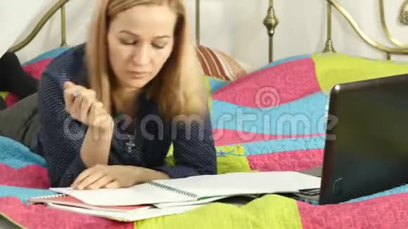 学生躺在家里的床上在笔记本电脑上工作的女人在线教育4K视频的预览图