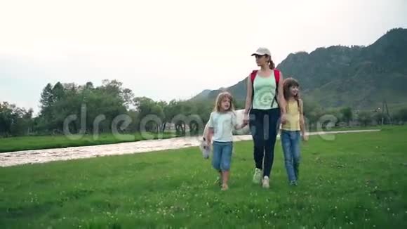 母亲带着女儿在草地上散步带着牧马幸福的家庭旅行慢动作视频的预览图