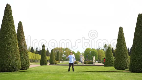 有趣的白种人年轻男子在夏天的晴天公园的绿草草坪上跳舞视频的预览图
