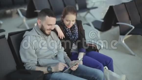 那家伙和穿着休闲服装的女孩正看着平板电脑屏幕笑着视频的预览图
