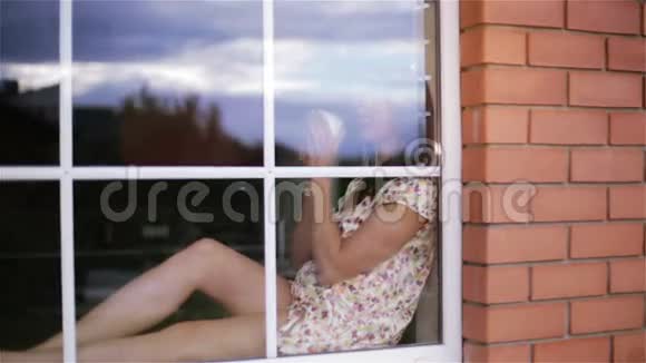 体贴悲伤的黑发中年妇女穿着睡衣坐在窗台上视频的预览图