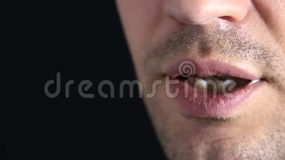 一个人悄悄地走进镜头嘴唇的特写在黑色背景下低语视频的预览图
