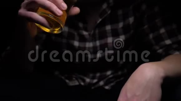 一个人在黑暗中喝啤酒没有脸的框架手拿一杯冷鲜饮料特写镜头4k视频的预览图