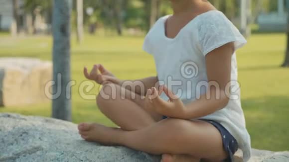 小女孩在美丽的公园里冥想背景是棕榈树视频的预览图