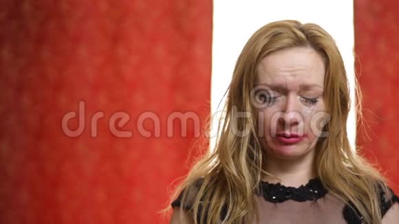 美丽悲伤的女人红色的口红和化妆在红色的白色背景下哭泣化妆和睫毛膏涂抹视频的预览图