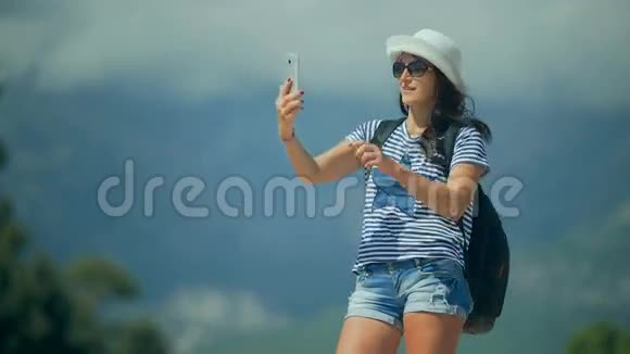 漂亮快乐的女人在山上用智能手机拍照视频的预览图