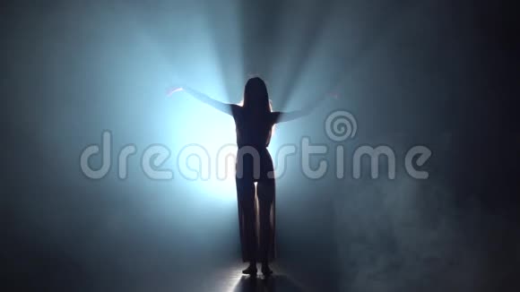 在黑暗的演播室里女人在聚光灯下跳舞的慢动作视频的预览图