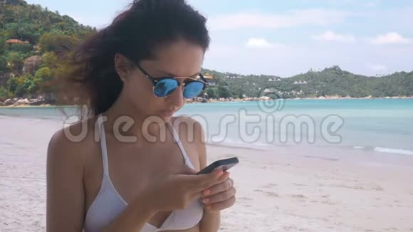 在海滩上使用手机的女人视频的预览图
