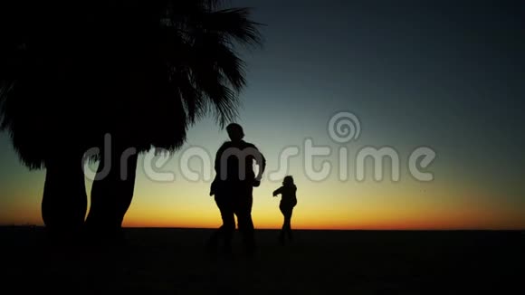 日落背景下的家庭游戏孩子们和父亲在海边玩耍的剪影视频的预览图
