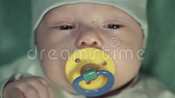一个刚出生的小男孩的肖像穿着温和的绿色西装带着一个黄色的奶嘴视频的预览图