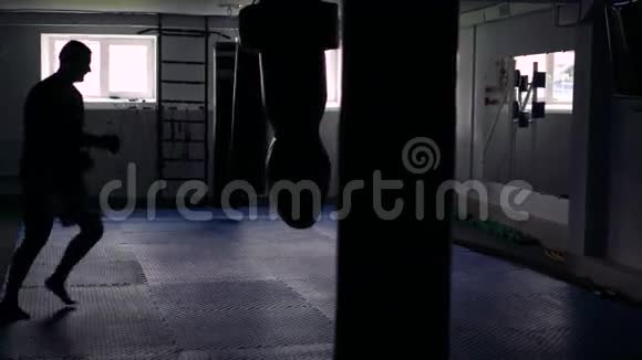 在黑暗的健身房里拳击手训练带着沙袋4k视频的预览图