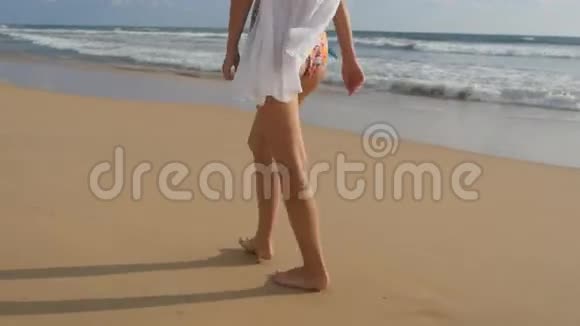 女足踏沙带海波背景穿着泳衣和衬衫的美女在海边散步视频的预览图