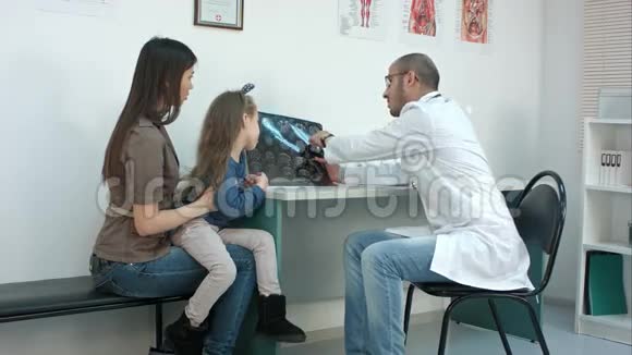 医生向年轻母亲展示X射线图像让她的女儿开心视频的预览图