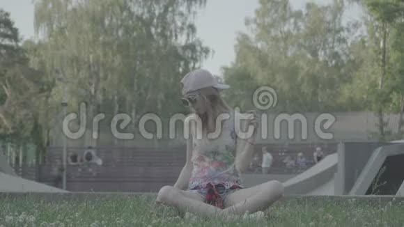 一个年轻的女人坐在公园里听她最喜欢的曲调颜色简介视频的预览图