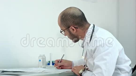 忙碌的男医生在医院的办公室里处理医疗表格和文件视频的预览图
