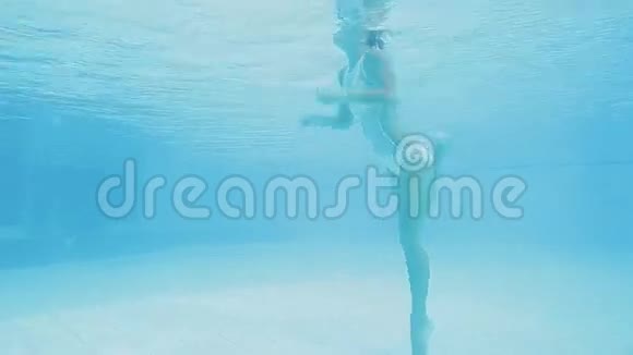 美丽的金发女人在游泳池里潜水和游泳视频的预览图