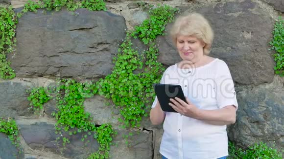 使用平板电脑的老年妇女背景中野生石头的复古墙视频的预览图