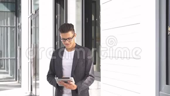 年轻的商人在现代建筑的背景下使用平板电脑视频的预览图