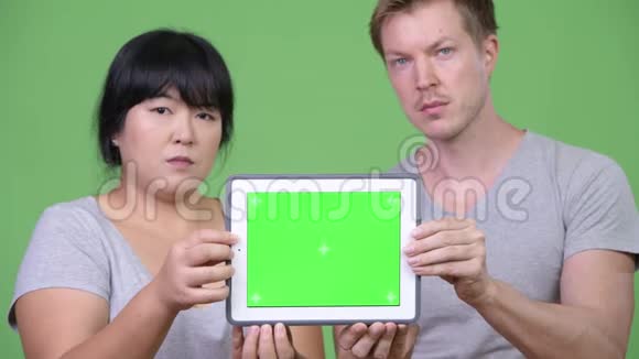 年轻幸福的多民族夫妇一起展示数字平板电脑视频的预览图