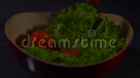 黑色背景下碗中的番茄和生菜叶视频的预览图