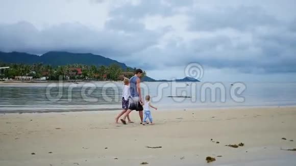 幸福的家庭和孩子们沿着海滩散步视频的预览图