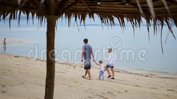 幸福的家庭和孩子们沿着海滩散步视频的预览图