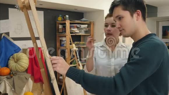 女艺术家帮助她的男学生画画画架视频的预览图