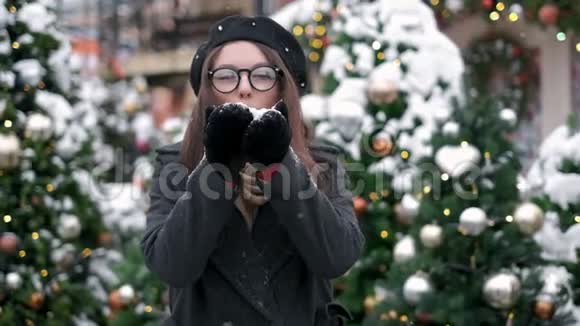 美丽的冬天女孩在市中心吹雪户外飞翔的雪花快乐的年轻女人有乐趣冬季和视频的预览图