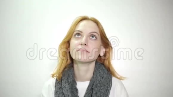 穿着白色毛衣和灰色围巾揉着鼻子的红头发的漂亮女人视频的预览图