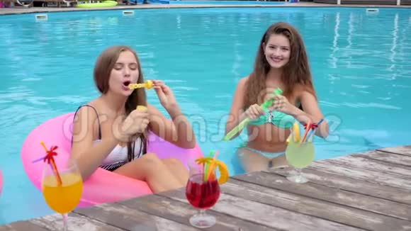 穿着泳衣的女朋友在游泳池里吹肥皂泡鸡尾酒会穿着泳衣休息的漂亮女孩视频的预览图