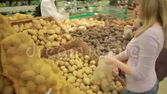 一个女人在超市的蔬菜货架上买蔬菜土豆视频的预览图