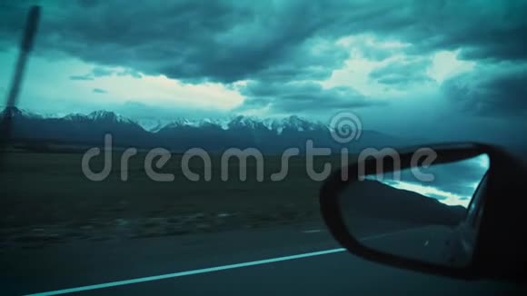 开车旅行傍晚的雪山景色透过后视镜可以看到多云的天空视频的预览图