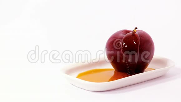 白盘红苹果上浇蜜的照片视频的预览图