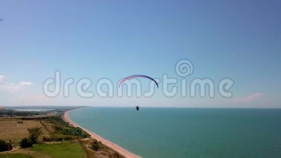 空中观景台滑翔伞飞越海岸线滑翔伞的翅膀被风吹动一排大海和视频的预览图