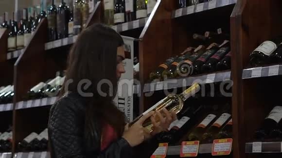 年轻女孩在超市的酒区挑选葡萄酒视频的预览图