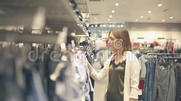 年轻女孩在时尚商场购物挑选新衣服视频的预览图