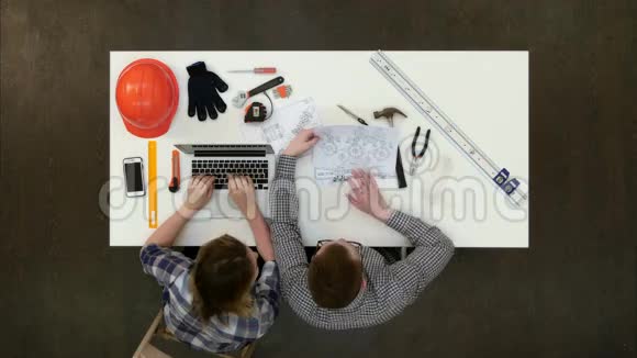 建筑师在设计蓝图而女性同事在手提电脑上打字视频的预览图