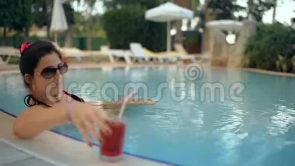 美丽的女士在游泳池喝鸡尾酒放松视频的预览图