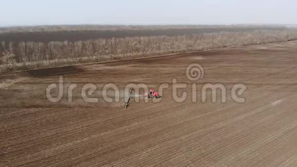 4空中镜头现代红色拖拉机在农业领域在阳光明媚的日子拖拉机耕地拖拉机培育视频的预览图