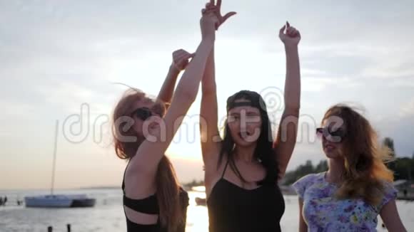 幸福三女在海边举起手来年轻的女人在度假时在闪亮的大海上跳舞女孩们玩得很开心视频的预览图