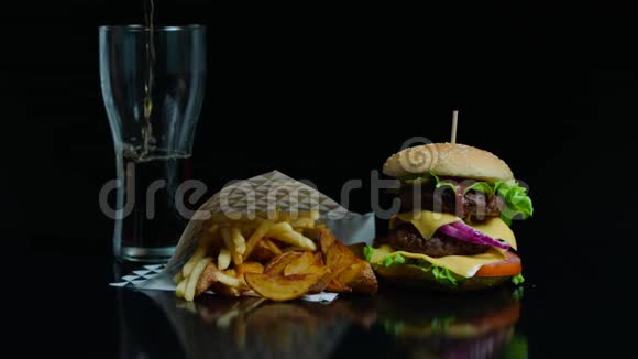 在黑色背景下倒入可口可乐和美味汉堡炸薯条用于商业视频的预览图
