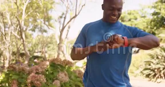 运动员在慢跑后微笑着看着他的智能手表视频的预览图