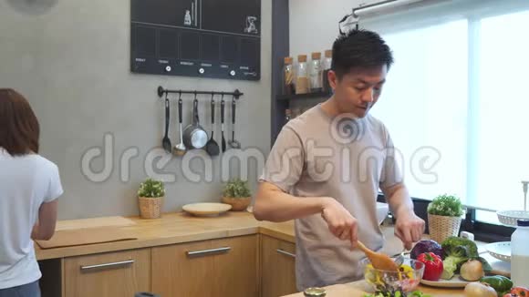 亚洲人在厨房里准备沙拉食物美丽快乐的亚洲夫妇正在厨房做饭视频的预览图
