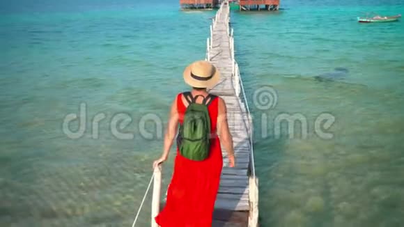 穿着红色长裙走在码头上的美女PhuQuoc岛旅行者的女人带着一个视频的预览图