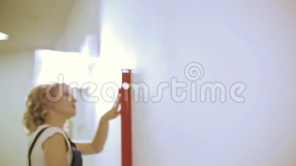 美丽的年轻女子与精神水平测量墙在新的家视频的预览图