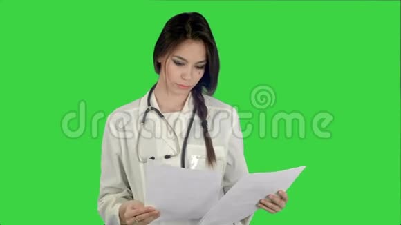 年轻女医生在绿色屏幕上阅读病人的病史表格Chroma键视频的预览图