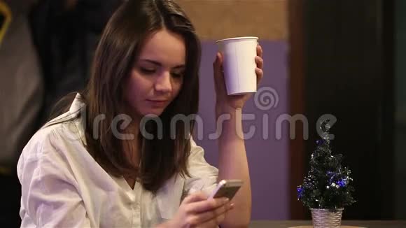 年轻女孩喝咖啡写短信问候朋友新年快乐视频的预览图