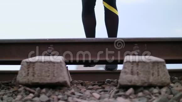 特写女性运动腿穿着黑色运动鞋和裤腿在铁轨上跳跃在铁路上在夏天女性视频的预览图