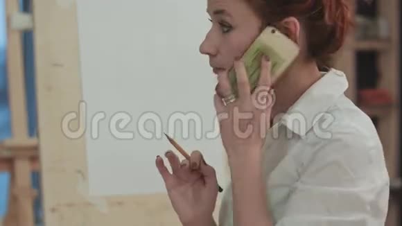 姜女艺术家在画架旁边打电话视频的预览图
